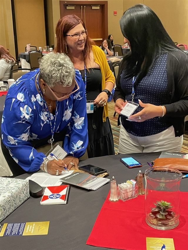 Regina signing a copy of Leadership Lessons with conference attendees.
